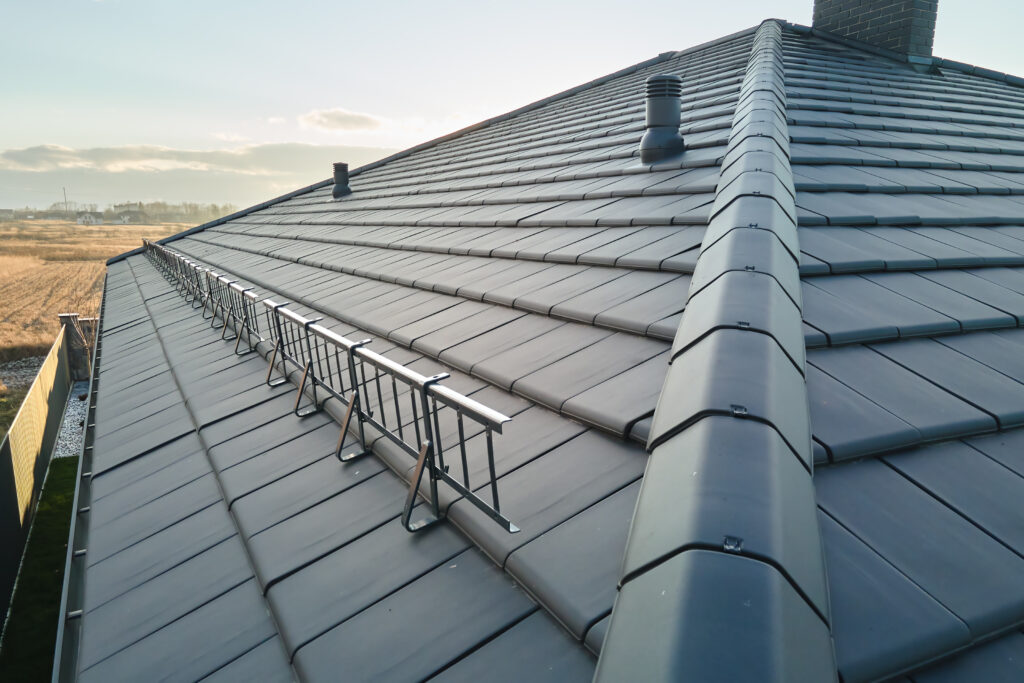 Closeup of house roof top covered with ceramic shingles. Tiled covering of building.