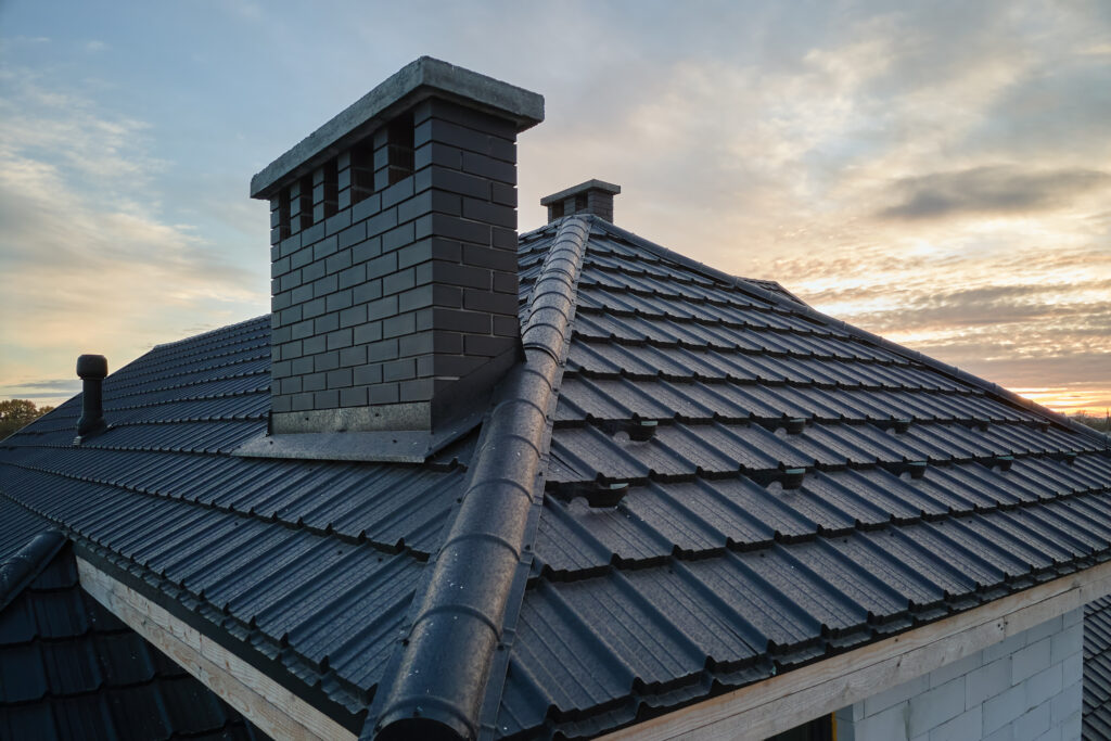 Snow guard for safety in winter on house roof top covered with ceramic shingles. Tiled covering of building.